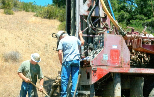 2 of the crew monitor the progress of the drilling.